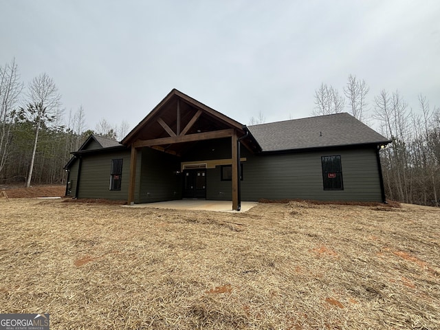 rear view of property featuring a patio area and roof with shingles