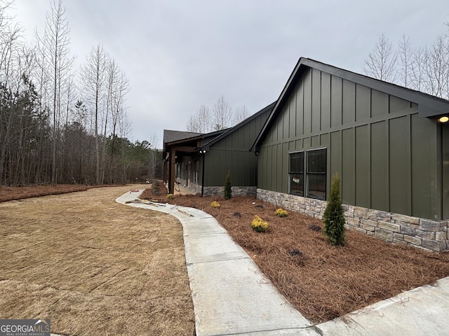 view of side of home featuring board and batten siding and stone siding