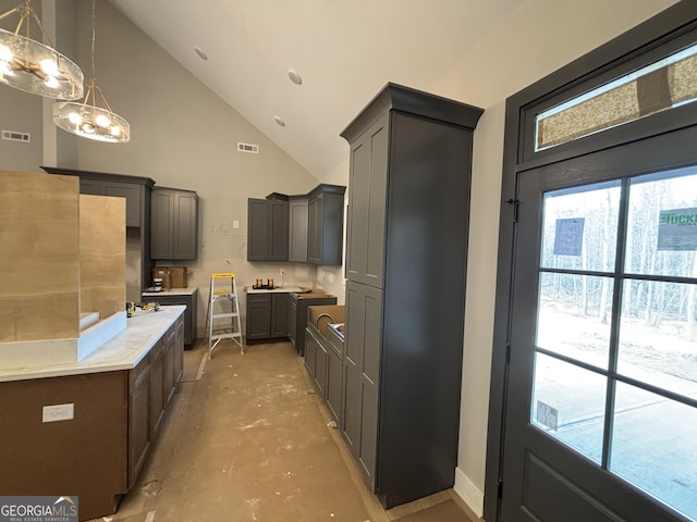 kitchen with high vaulted ceiling, light countertops, visible vents, and concrete floors