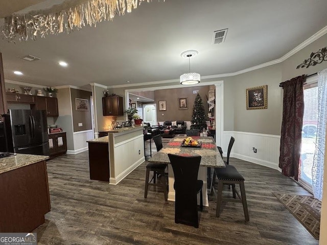 dining space with dark wood-style floors, wainscoting, visible vents, and crown molding