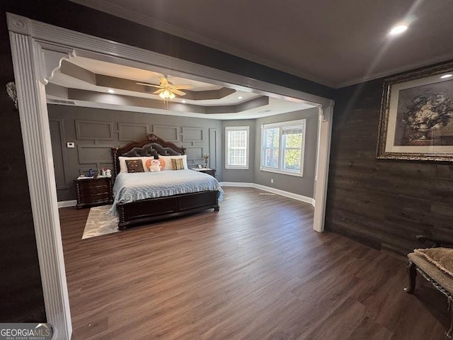 bedroom with dark hardwood / wood-style flooring, a tray ceiling, ceiling fan, and crown molding