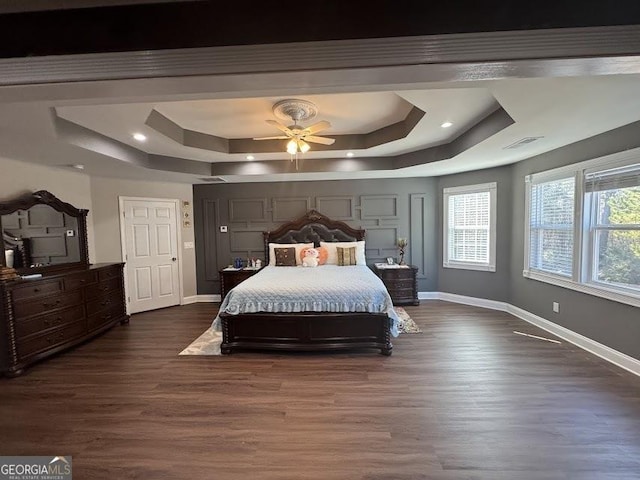 bedroom with visible vents, baseboards, a raised ceiling, and dark wood-style flooring