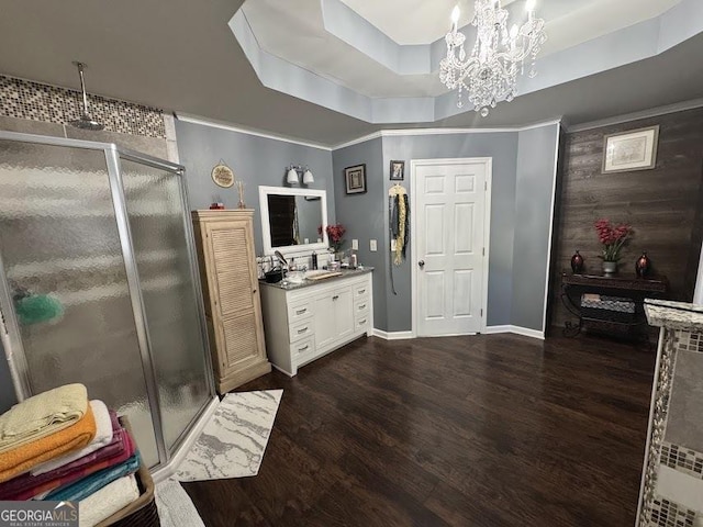 bathroom featuring an inviting chandelier, an enclosed shower, a tray ceiling, vanity, and hardwood / wood-style flooring