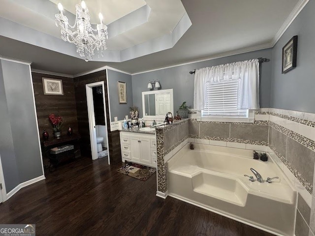 bathroom featuring a notable chandelier, hardwood / wood-style floors, toilet, a bathtub, and vanity