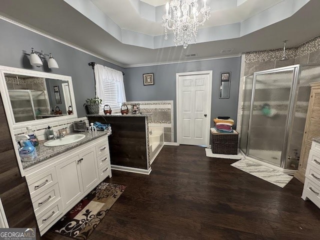 bathroom with shower with separate bathtub, vanity, a tray ceiling, and hardwood / wood-style floors