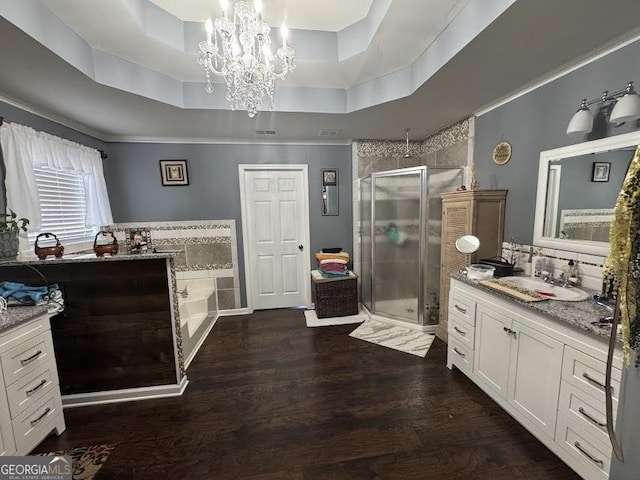 full bath with a raised ceiling, wood finished floors, a garden tub, vanity, and a shower stall