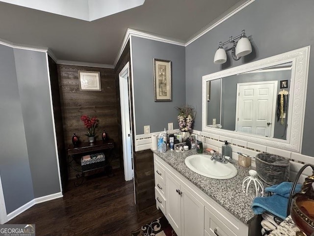 bathroom with wood finished floors, vanity, baseboards, ornamental molding, and backsplash