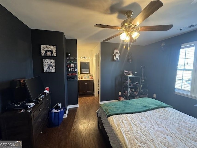 bedroom with ceiling fan, dark wood-type flooring, and ensuite bath