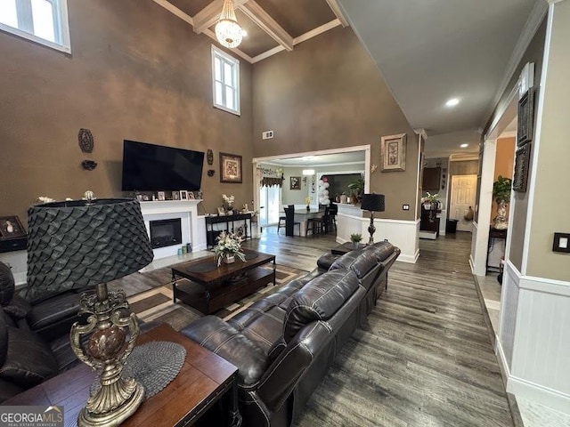 living area with a glass covered fireplace, wainscoting, crown molding, and wood finished floors