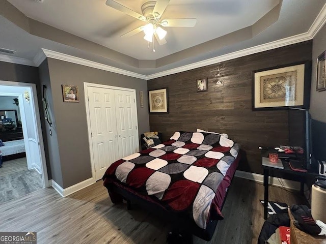 bedroom featuring wood-type flooring, a closet, ceiling fan, and ornamental molding