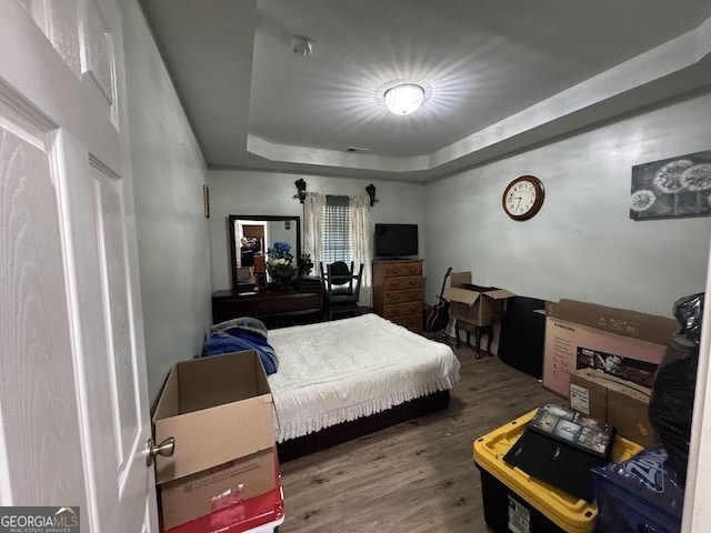 bedroom with hardwood / wood-style floors and a raised ceiling