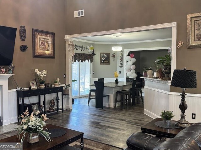 living room featuring hardwood / wood-style floors, crown molding, a high ceiling, and beamed ceiling