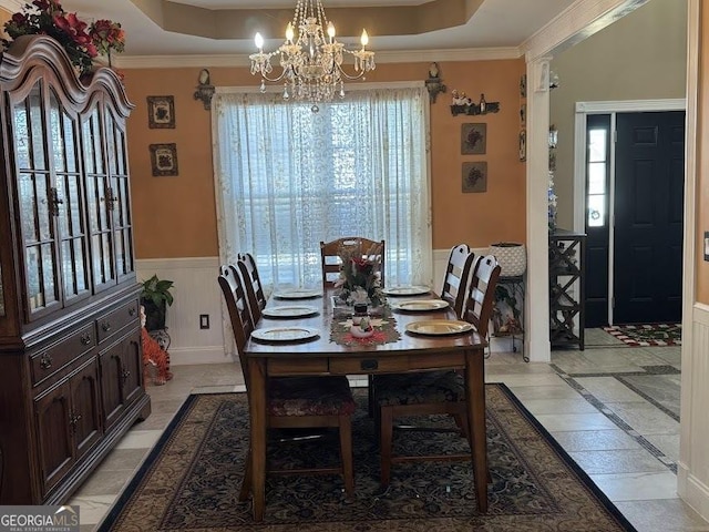 dining space with a raised ceiling, a notable chandelier, and crown molding