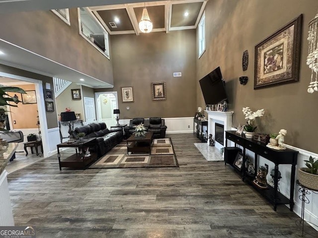 living area featuring dark wood finished floors, visible vents, a fireplace with flush hearth, coffered ceiling, and beamed ceiling