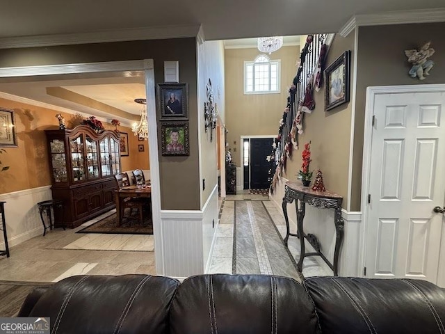 hall featuring a chandelier, wainscoting, and crown molding