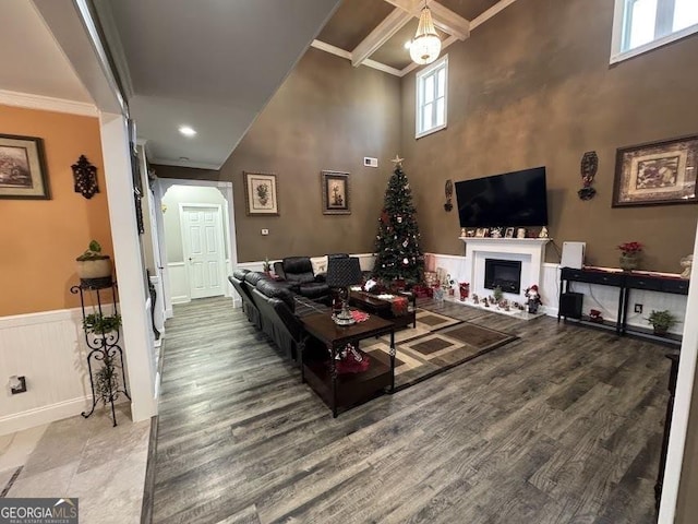 living room featuring wood-type flooring, a towering ceiling, and crown molding