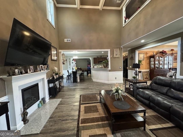 living room with a fireplace with flush hearth, dark wood finished floors, visible vents, and crown molding