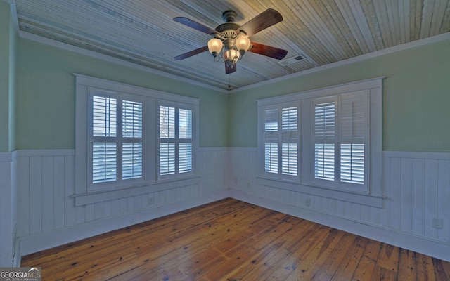 empty room with wooden walls, hardwood / wood-style flooring, ceiling fan, and ornamental molding