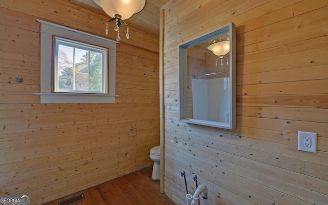 bathroom with wood walls, toilet, and wood-type flooring