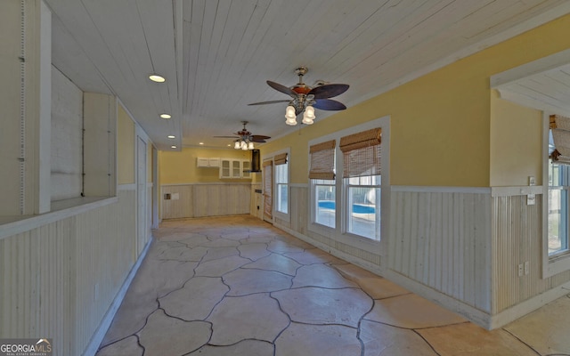 interior space featuring ceiling fan, wooden ceiling, and wooden walls