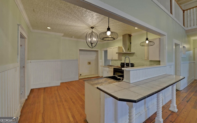 kitchen featuring extractor fan, crown molding, pendant lighting, black electric range, and light hardwood / wood-style floors