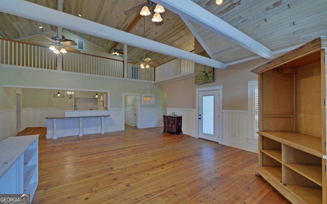 unfurnished living room featuring beamed ceiling, light wood-type flooring, high vaulted ceiling, and ceiling fan