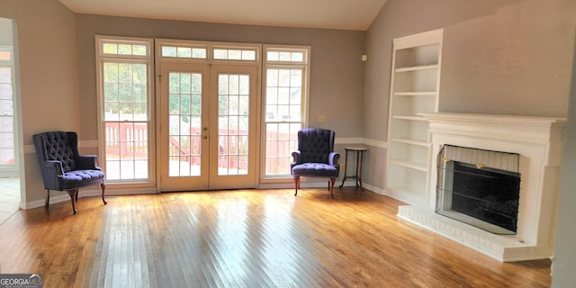 unfurnished room with a healthy amount of sunlight, light hardwood / wood-style floors, a fireplace, and built in features