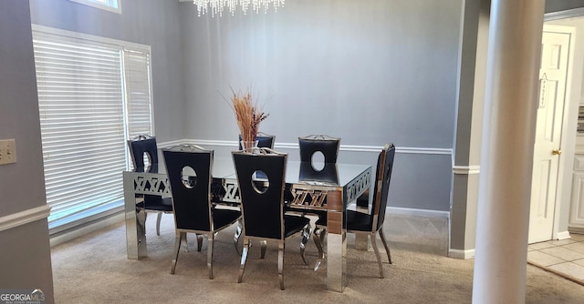 carpeted dining room featuring an inviting chandelier and ornate columns