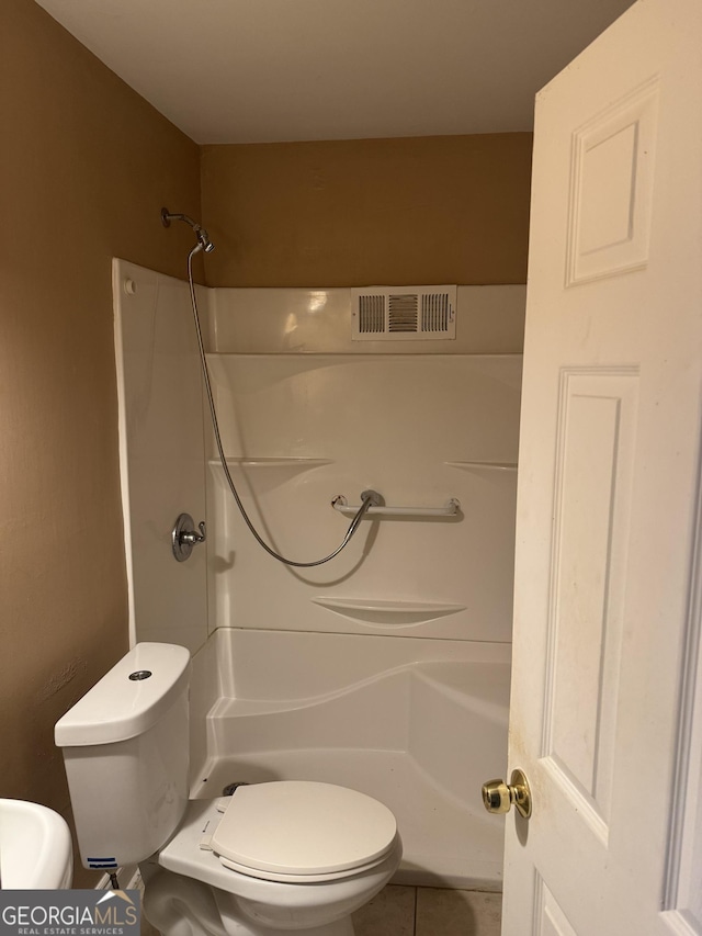 bathroom with tile patterned flooring, toilet, and a shower