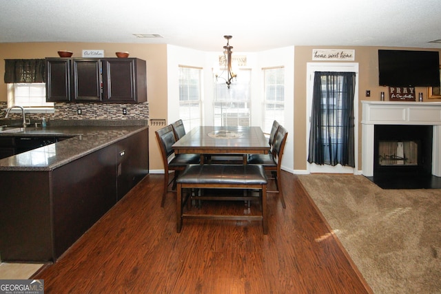 dining space featuring a notable chandelier, a wealth of natural light, dark wood-type flooring, and sink