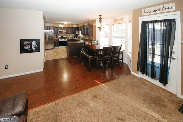 dining room with sink, wood-type flooring, and a notable chandelier