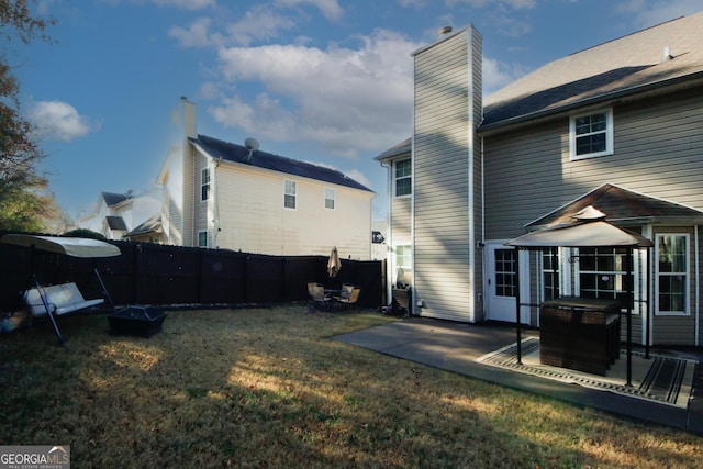 back of property featuring a yard, a patio, and an outdoor fire pit