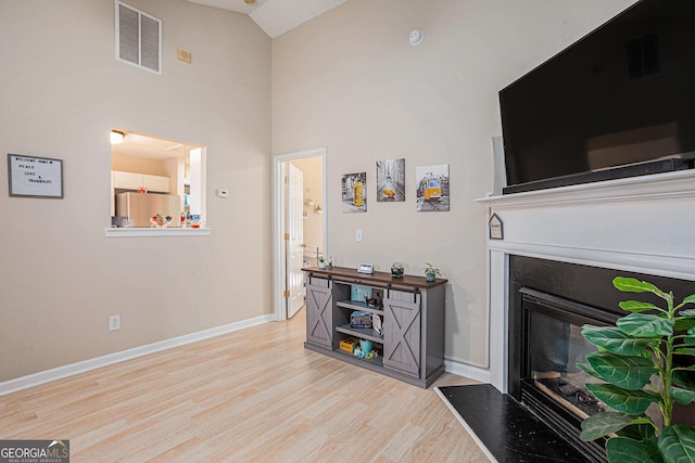 living room with light hardwood / wood-style floors and a high ceiling