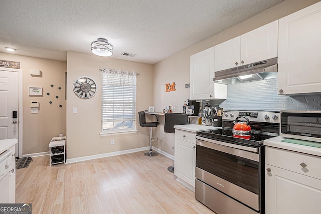 kitchen with decorative backsplash, a textured ceiling, stainless steel electric range oven, light hardwood / wood-style floors, and white cabinetry