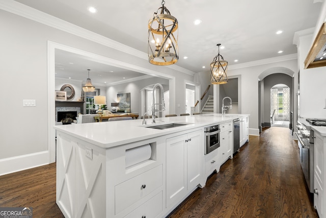 kitchen with dark hardwood / wood-style flooring, stainless steel appliances, a kitchen island with sink, white cabinetry, and hanging light fixtures