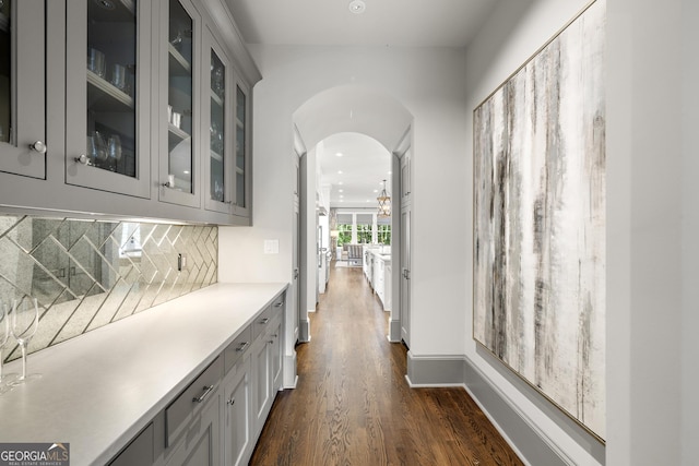 bar featuring tasteful backsplash, gray cabinets, and dark hardwood / wood-style flooring