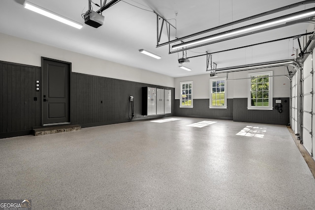 garage featuring a garage door opener and wooden walls