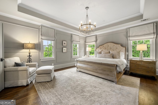 bedroom with an inviting chandelier, crown molding, dark wood-type flooring, and a tray ceiling