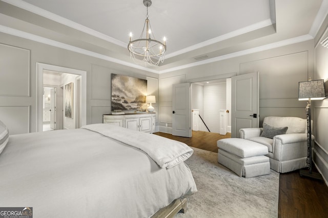 bedroom featuring hardwood / wood-style floors, an inviting chandelier, a raised ceiling, and crown molding