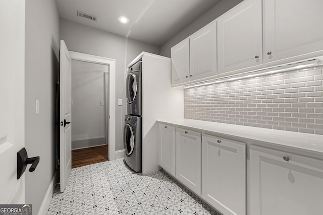 laundry room with cabinets and stacked washer and clothes dryer