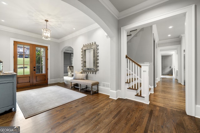 foyer entrance featuring a notable chandelier, ornamental molding, dark wood-type flooring, and french doors