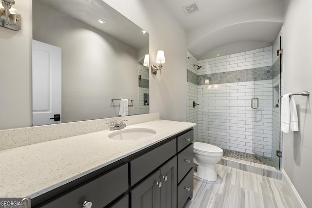 bathroom featuring vanity, toilet, and a shower with shower door