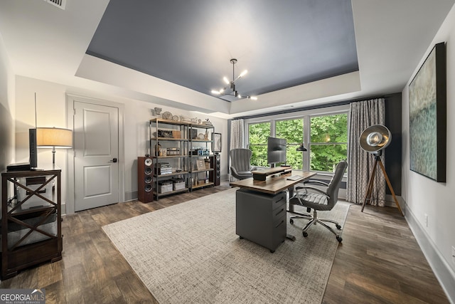 office space with a raised ceiling, dark hardwood / wood-style floors, and a notable chandelier