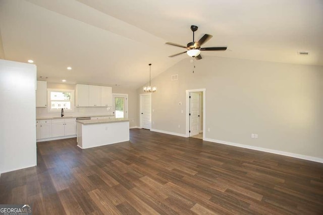 unfurnished living room with ceiling fan with notable chandelier, dark wood-type flooring, lofted ceiling, and sink