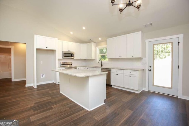 kitchen featuring stainless steel appliances, a kitchen island, a wealth of natural light, and lofted ceiling