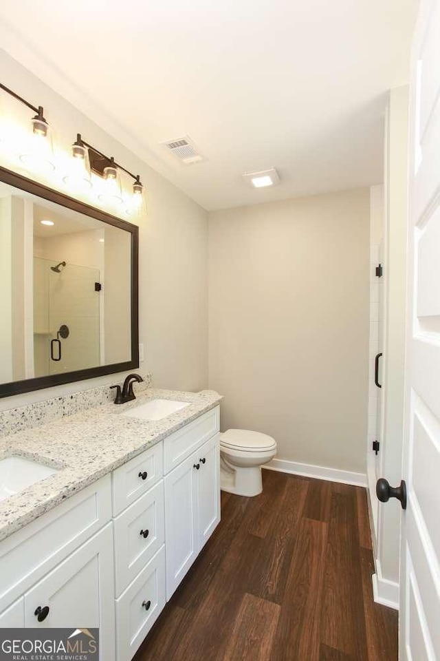 bathroom with wood-type flooring, vanity, toilet, and a shower with shower door