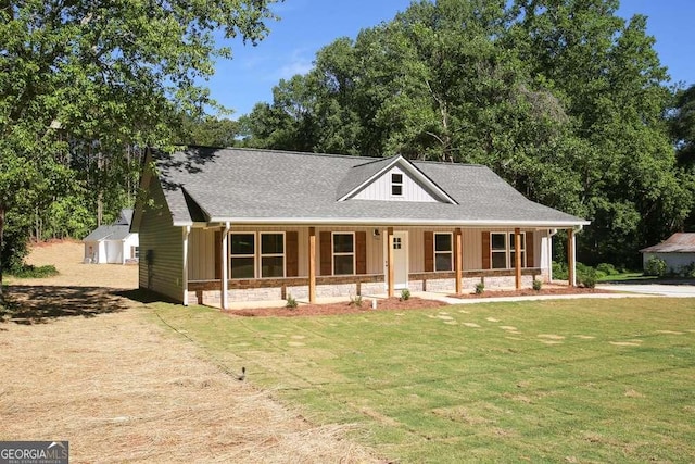 view of front of house featuring covered porch, an outbuilding, and a front yard