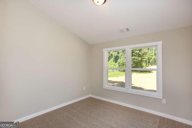 carpeted spare room featuring vaulted ceiling