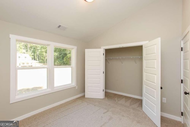 unfurnished bedroom with light carpet, a closet, and lofted ceiling