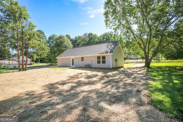 exterior space with central AC unit and a lawn